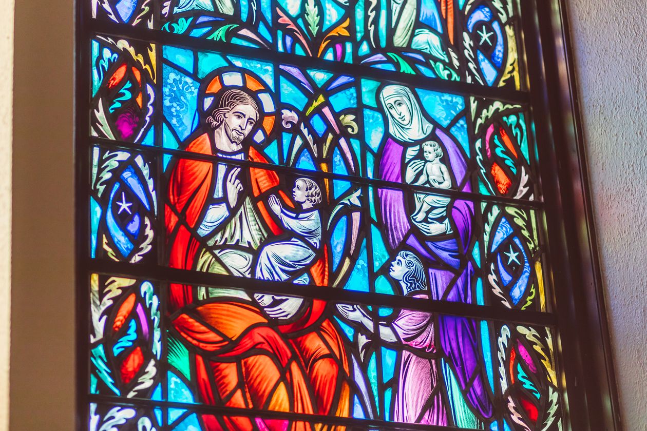 Stained glass depicting Jesus welcoming children