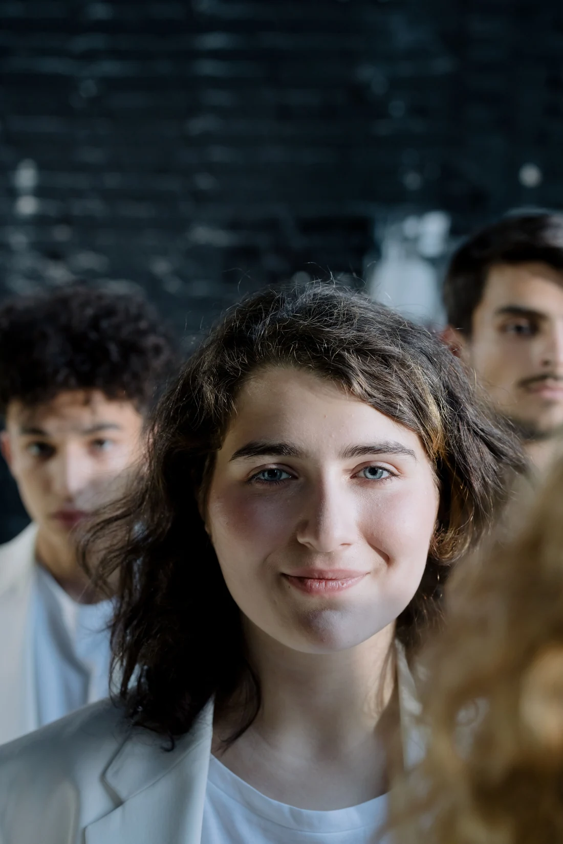 A woman with other adults softly out of focus behind her